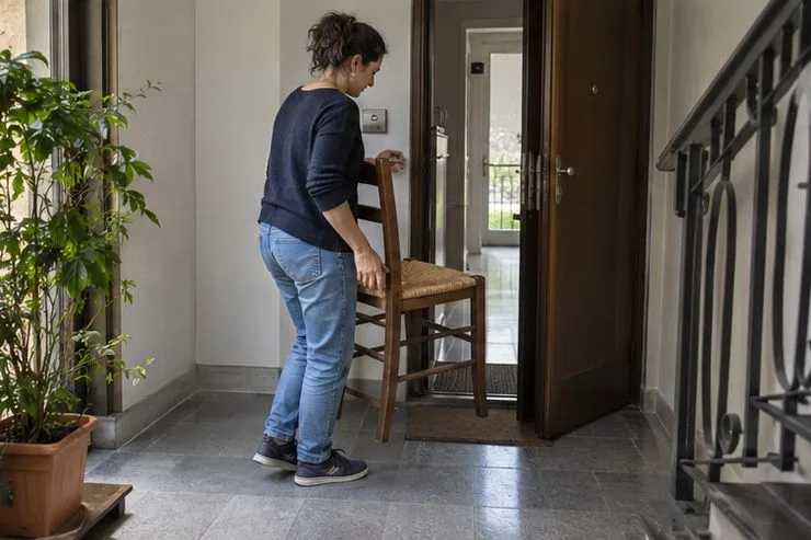 Una residente sposta una sedia verso l’ingresso del condominio lasciando libero il passaggio.