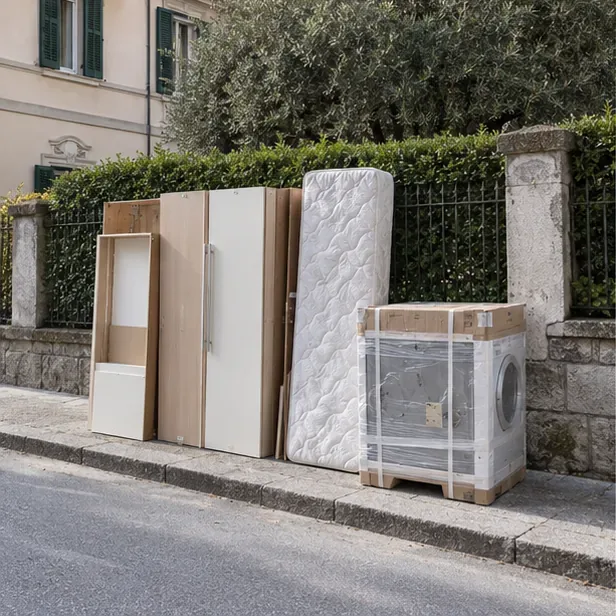 Un armadio smontato, un materasso e una lavatrice imballata sono ordinati vicino al bordo strada senza occupare la carreggiata.