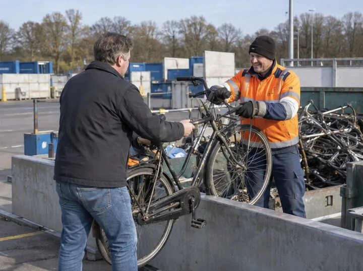 Een inwoner overhandigt een oude stadsfiets aan een medewerker bij een gemeentelijk recyclingperron