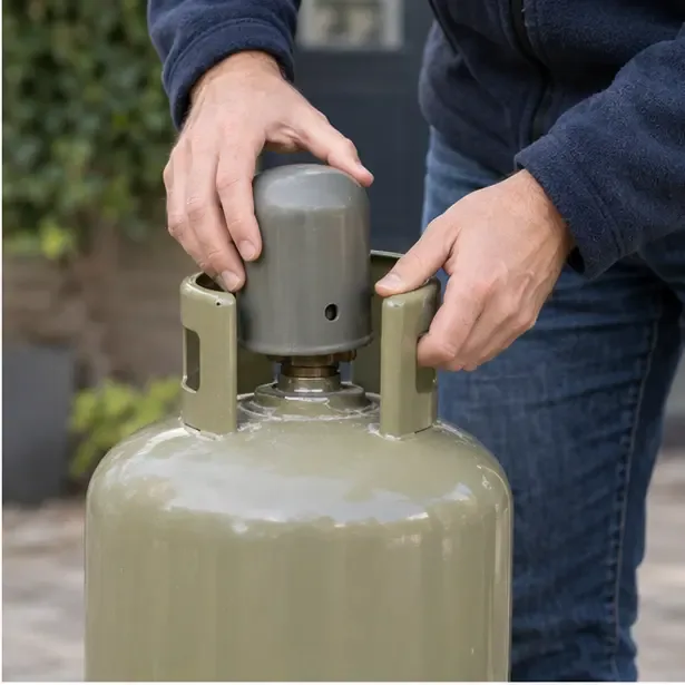 Handen plaatsen een beschermkap over het ventiel van een rechtopstaande gasfles