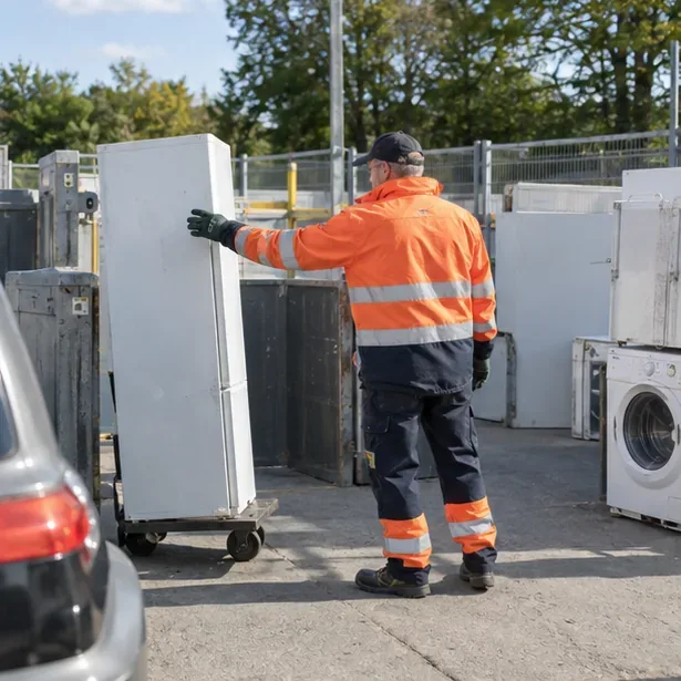 Een medewerker neemt een oude koelkast in bij een gemeentelijke milieustraat