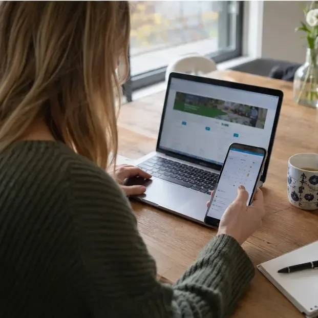 Een bewoner controleert op laptop en telefoon de gemeentelijke afvalinformatie
