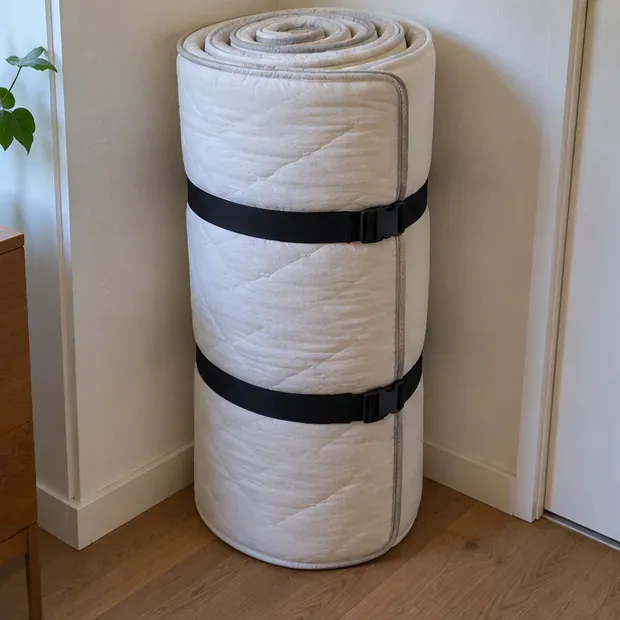 Een matras is binnenshuis strak opgerold en met twee banden vastgezet.