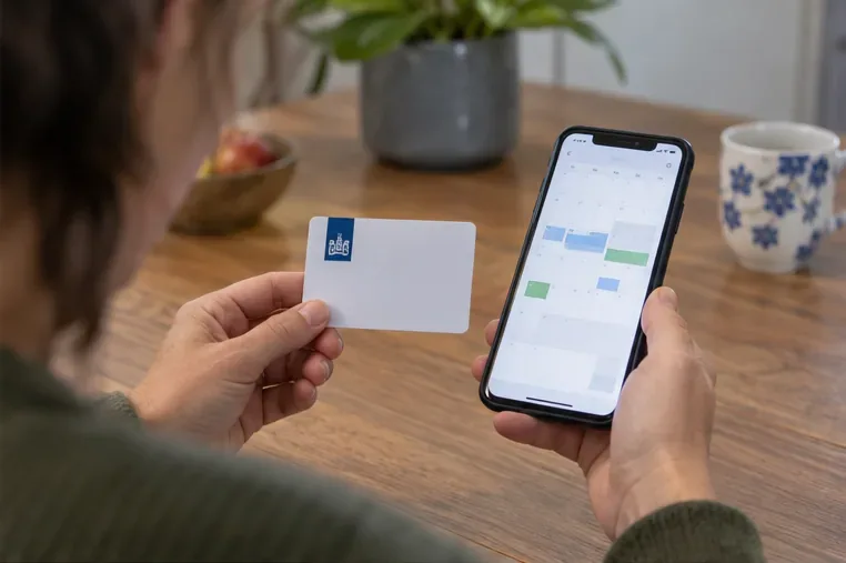 Een bewoner houdt een milieupas en telefoon met een afsprakenkalender bij elkaar