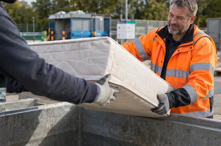 Een medewerker van een milieustraat neemt een oud matras aan bij een aparte afvalcontainer