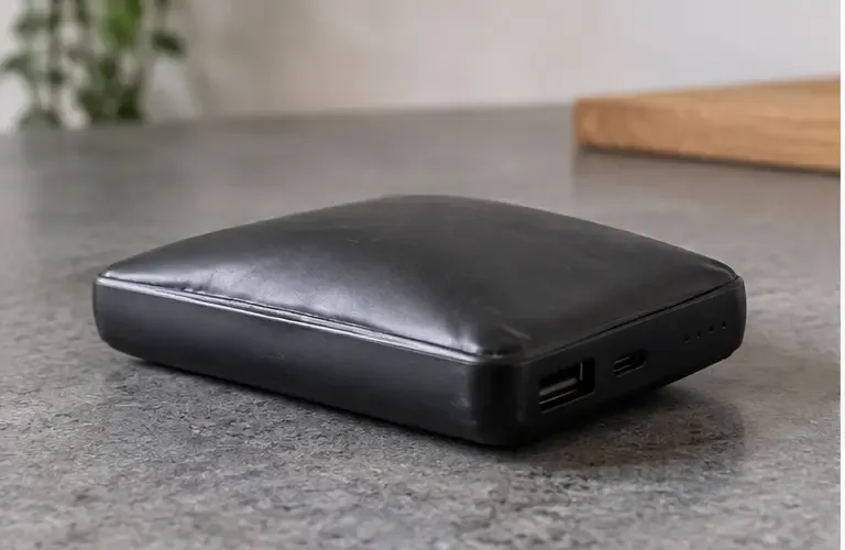 Een zichtbaar bolstaande en vervormde powerbank ligt op een werkblad zonder dat iemand hem aanraakt