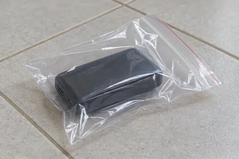 Een opgezwollen powerbank ligt afzonderlijk in een doorzichtig plastic zakje op een tegelvloer