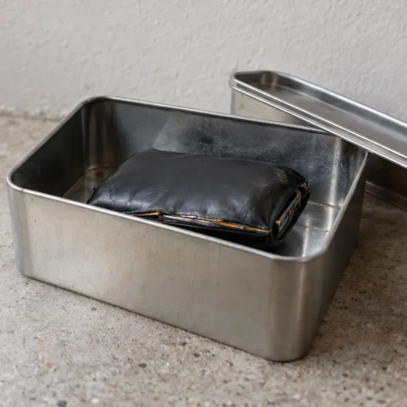 Een zichtbaar opgezwollen zwarte powerbank ligt geïsoleerd in een metalen bak op een harde ondergrond