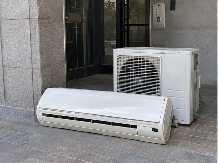 철거가 끝난 벽걸이 에어컨 실내기와 실외기가 건물 출입구 근처에 함께 놓인 모습