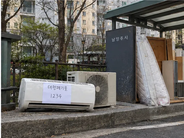 남양주시 공동주택의 지정 대형폐기물 배출장소에 실내기와 실외기가 배출번호 표시와 함께 놓여 있는 모습