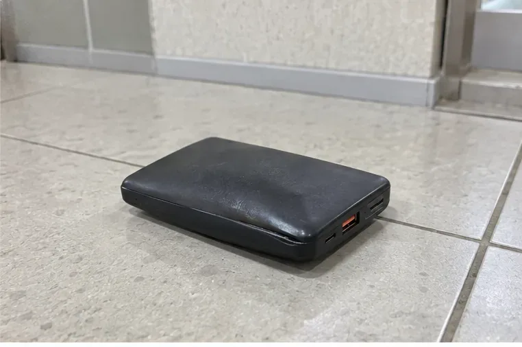 부푼 검은색 보조배터리를 타일 바닥의 주변 가연물이 없는 공간에 따로 둔 모습