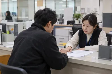 주민이 동 행정복지센터 민원 창구에서 직원과 서류를 확인하고 있다.