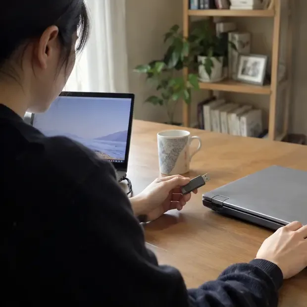 한 사람이 오래된 노트북의 파일을 USB 저장장치에 백업하고 있다