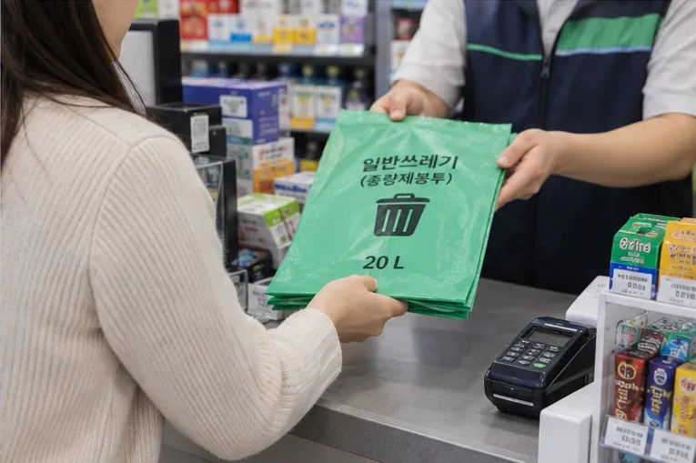 편의점 계산대에서 초록색 일반쓰레기 종량제봉투를 건네받는 모습