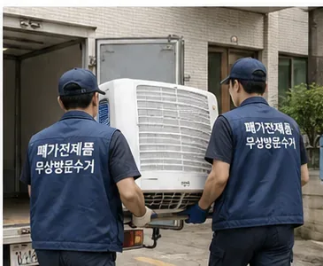 두 명의 수거 작업자가 에어컨 실외기를 운반해 차량에 싣는 모습