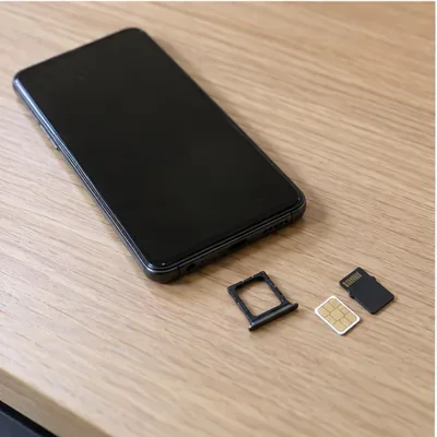 전원이 꺼진 스마트폰 옆에 분리한 유심 트레이와 microSD 카드가 놓인 모습