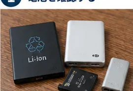 黒や銀色のリチウムイオン電池パックやモバイルバッテリーが木製の机に並んでいる様子