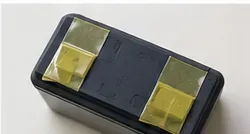 小型の充電式電池パックの金属端子をテープで覆っている様子
