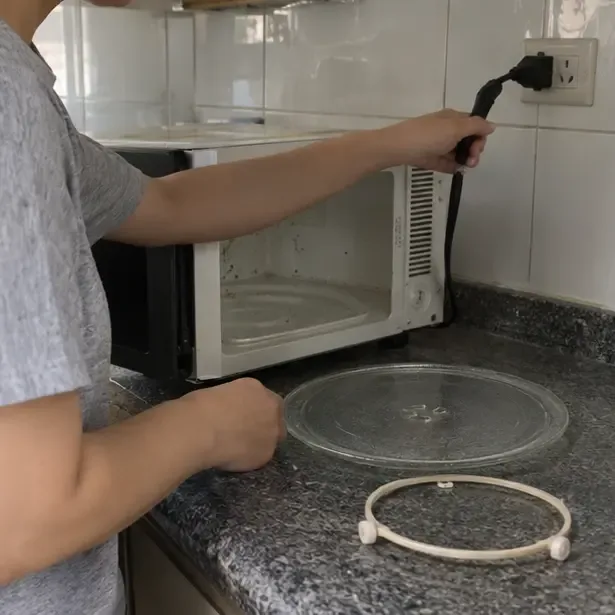 民眾拔下微波爐插頭並取出玻璃轉盤與滾輪配件