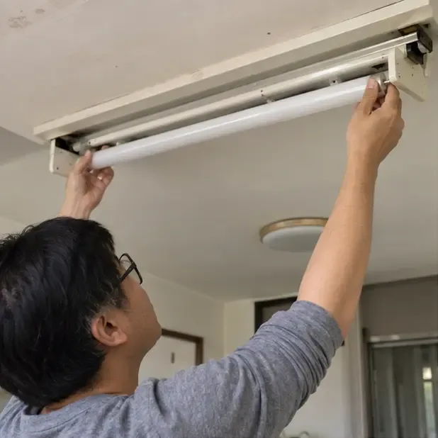 民眾在室內關閉並小心拆下天花板燈具中的直管日光燈