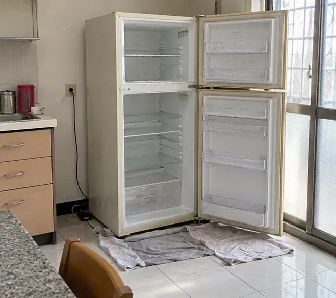 嘉義市住家廚房內已清空並打開門的舊冰箱，準備在回收前除霜與清理