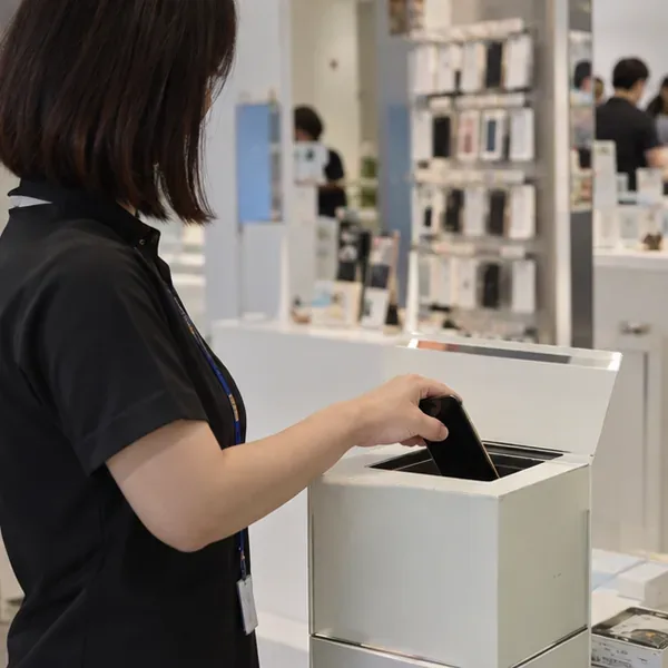 門市工作人員將舊手機放入店內的電子產品回收箱