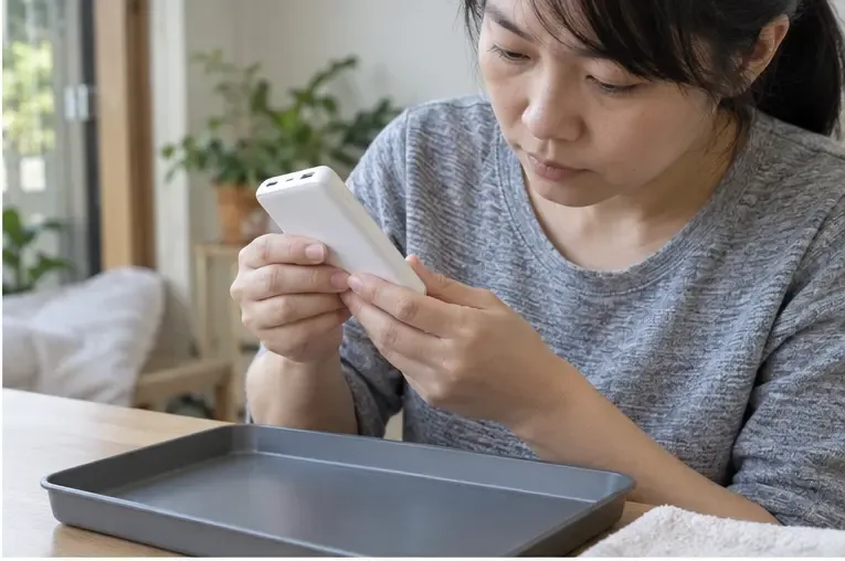 使用者在乾燥托盤旁檢查白色行動電源外殼是否平整，沒有拆開設備