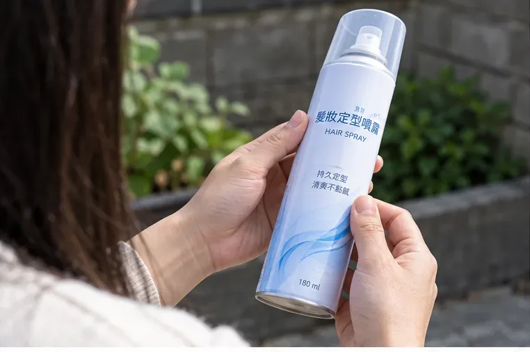 民眾在戶外查看一罐髮膠噴霧罐的罐身與噴頭，準備確認內容物是否已使用完畢