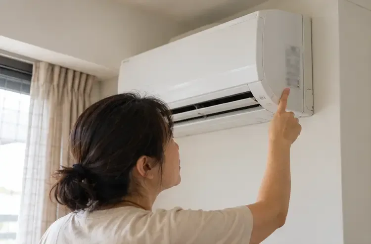 住戶在分離式冷氣室內機旁查看機身資料標籤，準備確認舊機規格