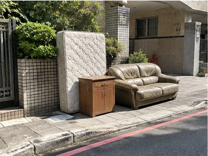 舊床墊、沙發與木櫃整齊放在住家外側可接近的位置，示意依約將大型垃圾搬到車輛可作業處