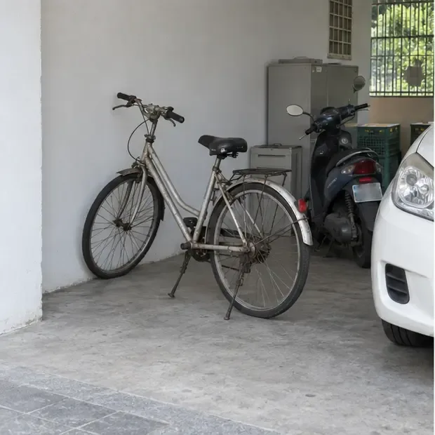 一台老腳踏車直立停放在有遮蔽的住宅車庫內，旁邊沒有占用道路或阻擋出入口