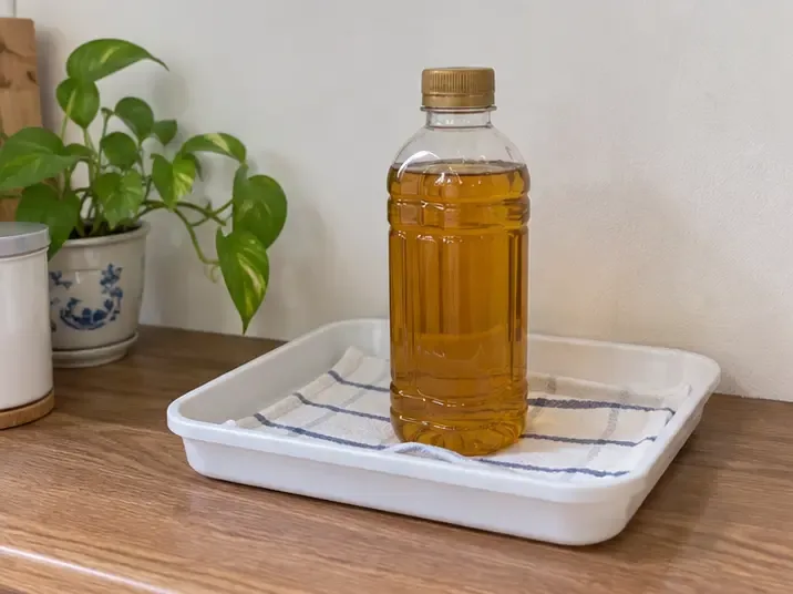 裝滿廢食用油的密封瓶直立放在托盤內，遠離廚房水槽與排水孔