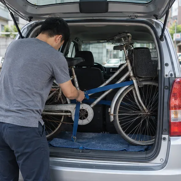 一名男子用藍色固定帶把腳踏車固定在小型車輛後廂內，示意自行載送前先做好安全固定
