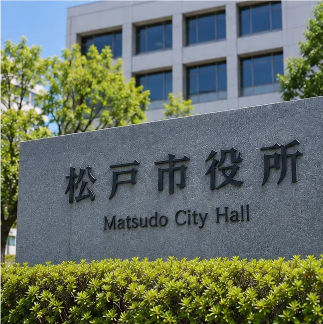 「松戸市役所」と表示された庁舎前の石碑と建物を写した場面