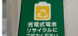 緑色の案内板に充電式電池のリサイクルを示す電池マークと文字が表示されている様子