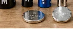 木製の台に置かれたCR表記のある銀色のリチウムコイン電池