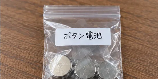 絶縁された複数の丸い電池を、ボタン電池と書かれた透明な小袋にまとめた様子