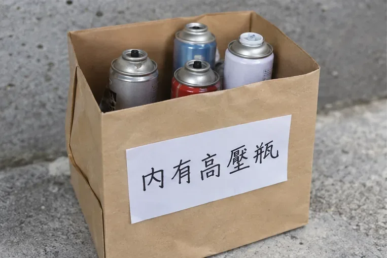 數個已排空的噴霧罐集中放入紙箱，紙箱外清楚標示內有高壓瓶