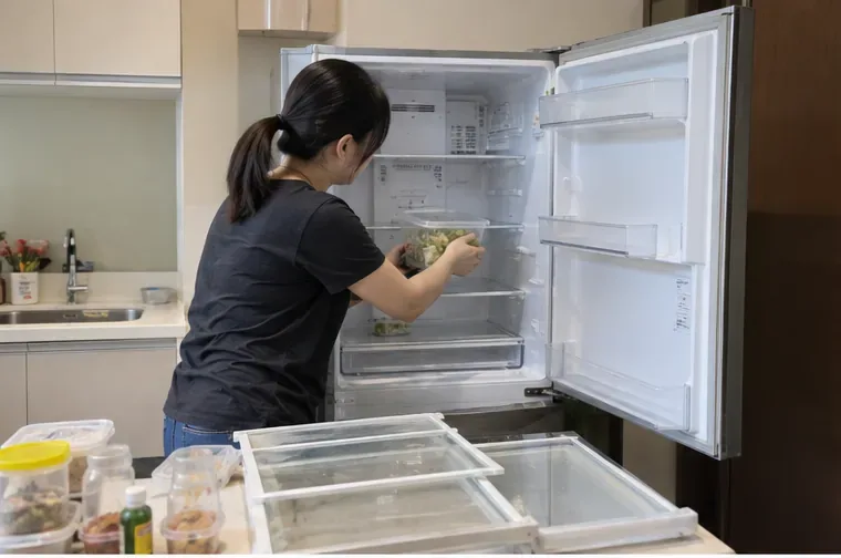 住戶在廚房把舊冰箱內的食物與容器取出，準備後續回收搬運