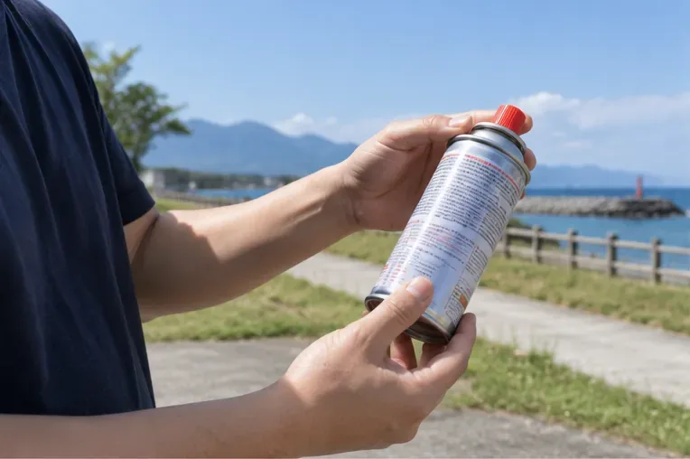 一名民眾在戶外雙手檢視卡式瓦斯罐的罐體與噴嘴