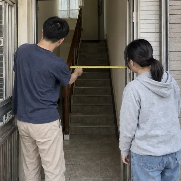 兩名住戶在住宅入口用捲尺確認沙發搬運通道的寬度