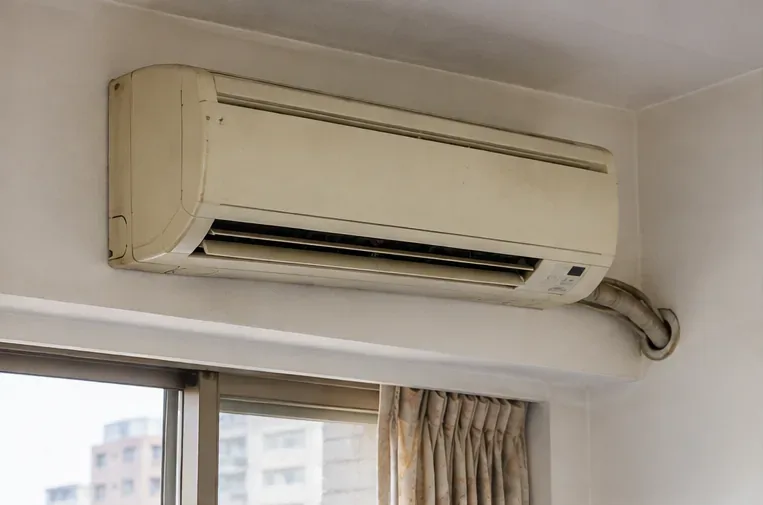 住家牆面上一台老舊分離式冷氣室內機，準備評估汰換與回收