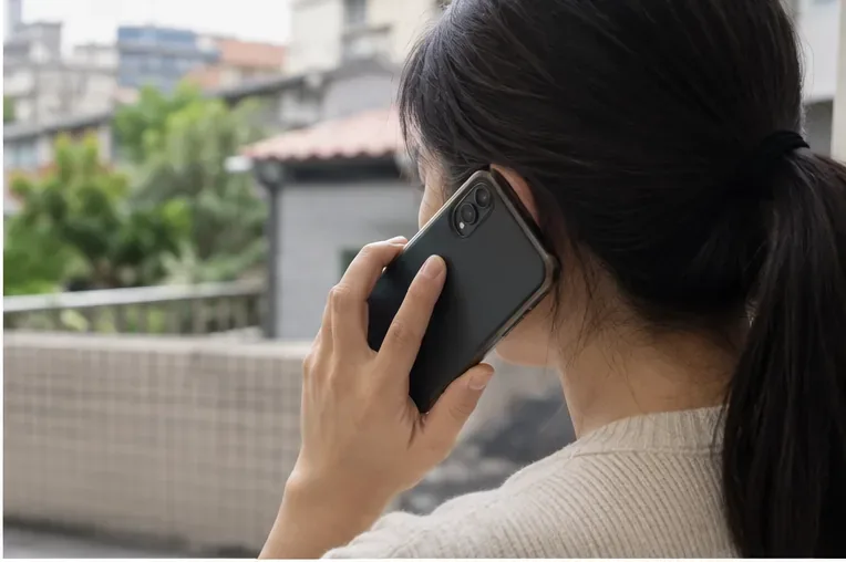 住戶在陽台用手機打電話，準備向頭份市清潔隊詢問舊沙發清運
