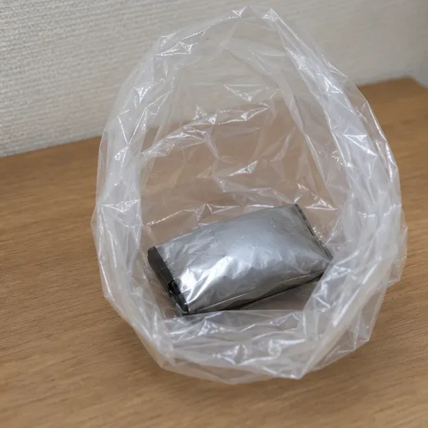 膨張して丸みを帯びた銀色のバッテリーを他の電池と分けて透明袋に入れた状態