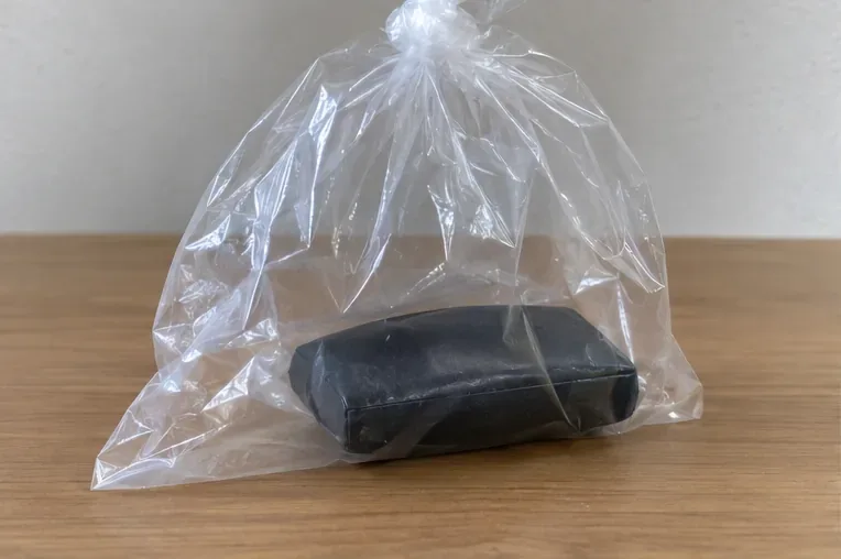 端子を絶縁した膨らんだ黒いモバイルバッテリーを単独で透明袋に入れた状態