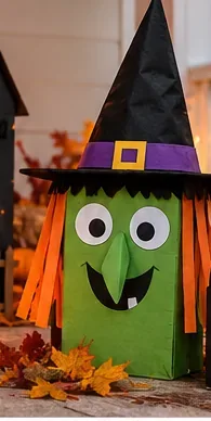 Figura alta di una strega di cartone verde con cappello a punta nero e capelli di carta arancione