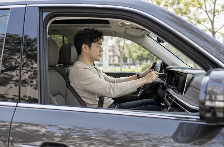 운전자가 SUV 운전석에서 시트 위치와 핸들까지의 거리를 살펴보는 모습