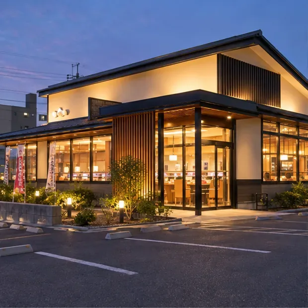 夕方に照明がともる日本の飲食店の外観と駐車スペース