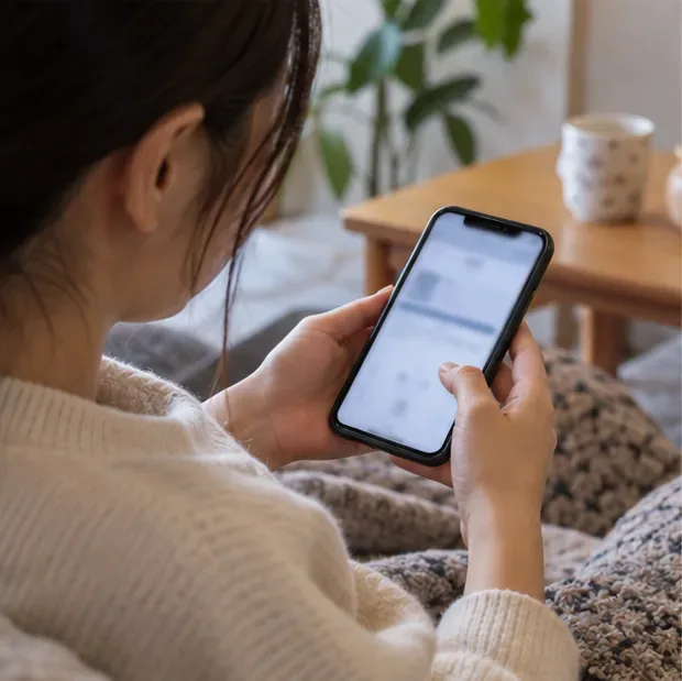 自宅でスマートフォンを操作し飲食店の予約を確認する人